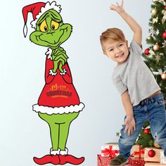 a young boy standing in front of a christmas tree with the grin face on it