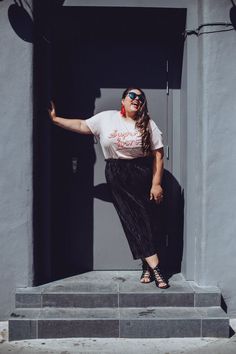 a woman standing on the steps in front of a building with her arms spread out