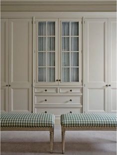 two benches in front of white cabinets with checkered fabric on the bottom and sides