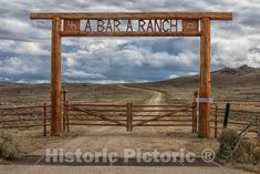 a wooden sign that reads, i'm a bar a ranch on the side of a dirt road