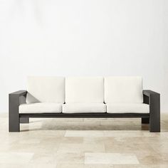 a black and white couch sitting on top of a tile floor next to a wall