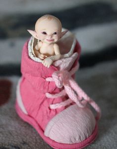 a small baby doll sitting in a pink shoe