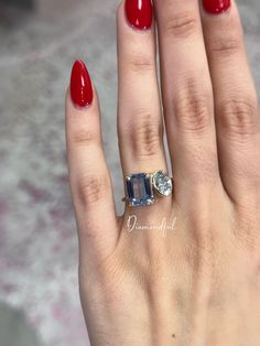 a woman's hand with red nail polish and an engagement ring on her finger