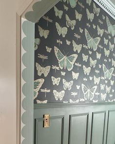 a green door with butterflies painted on the side and scalloped trim around it