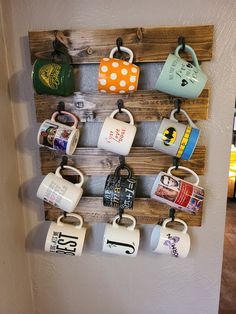 coffee mugs are hung on a wooden rack with magnets attached to the wall