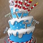 a three tiered cake decorated in blue and white icing with lots of candy sticks sticking out of it