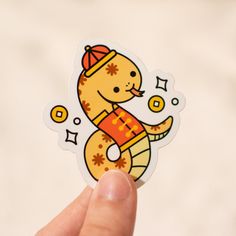 a hand holding up a sticker with a cartoon cat on it's back