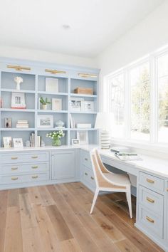 a home office with light blue cabinets and wood floors