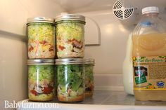 four mason jars filled with salad ingredients sitting on top of a refrigerator