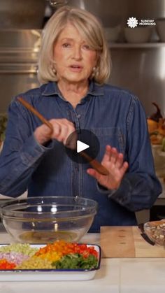 an older woman is preparing food in the kitchen with chopsticks and wooden spoon