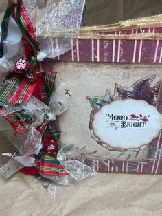 a christmas gift wrapped in ribbon and wrapping on top of a tablecloth covered box