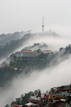 the city is covered in thick fog and low lying clouds as it sits on top of a hill