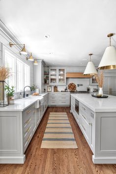 a large kitchen with white cabinets and wood flooring, along with an area rug in the middle