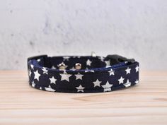 a black and white dog collar with stars on it, sitting on top of a wooden table