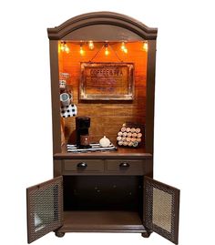 an old fashioned wooden cabinet with lights on the top and door open to display items