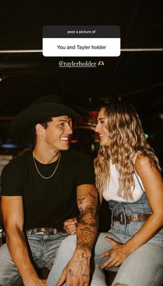 a man and woman sitting next to each other with tattoos on their arms, looking at each other