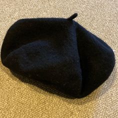 a black hat laying on the floor with it's top half covered in wool