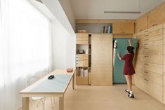 a woman standing in front of a blue refrigerator freezer next to a wooden table