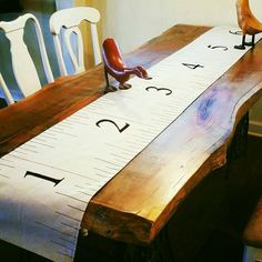 a wooden table topped with a ruler and two birds sitting on chairs next to it