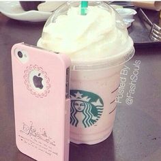 a starbucks drink with whipped cream and a cell phone case sitting on a table next to it