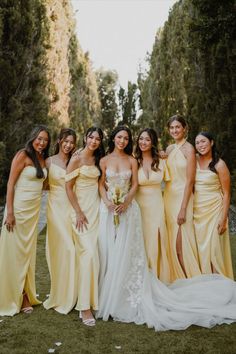 a group of women standing next to each other wearing yellow dresses and holding bouquets