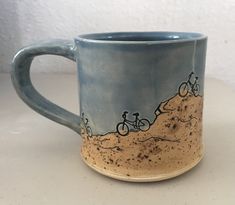 a coffee mug with two people riding bikes on the beach