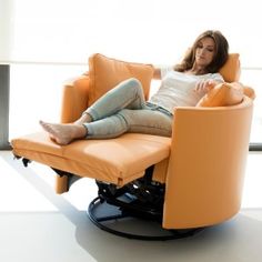 a woman sitting in an orange chair with her feet up on the armrests