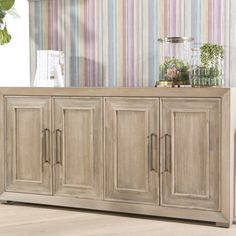 a sideboard with doors and drawers in front of a striped wall