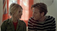 a man and woman sitting next to each other in front of a red wall with the words what happens now written on it