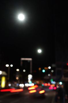 blurry image of city street at night with cars and lights in the foreground