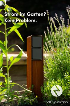 a wooden post sitting in the middle of a garden next to tall grass and flowers