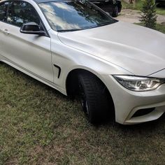 a white car parked on top of a grass covered field