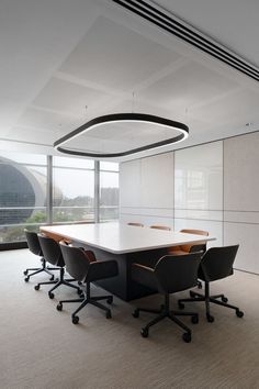 an empty conference room with black chairs and a white table in front of large windows