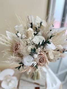 a vase filled with flowers and feathers on top of a table