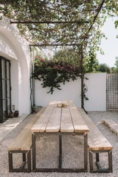 a wooden table sitting under a pergolated trellis