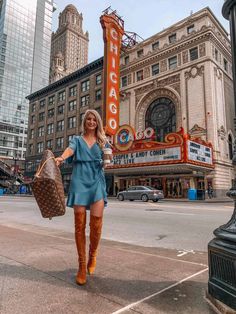 a woman is walking down the street in front of a chicago theater with her purse