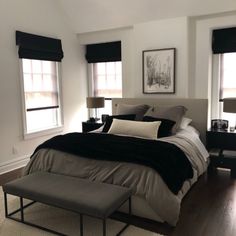 a large bed sitting in a bedroom next to two windows with black shades on them