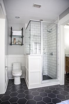 a bathroom with a toilet, shower and tiled flooring in black and white colors