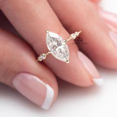 a woman's hand holding a ring with two pear shaped diamonds on top of it