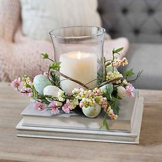 a candle sitting on top of a table next to an egg and flowers centerpiece