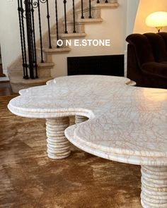 a white marble coffee table sitting on top of a brown carpeted floor next to a stair case