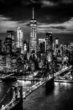 a black and white photo of the city skyline at night with lights in the buildings