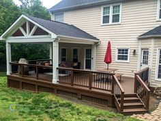 a deck with an umbrella on it in front of a house