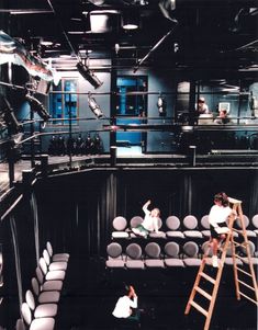 two people are sitting on chairs in the middle of a room with ladders and seats