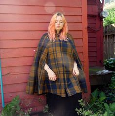 "This amazing Neiman-Marcus cape is in near perfect shape with no issues to note. Thick zipper up the front, which functions with ease, and a high collar to keep you warm. The caramel and navy plaid is offset by a satiny purple lining. One size will fit many, please ask questions if there are any fit concerns.  Measurement placements are estimated.  Shoulder-18\" Total Length-38.5\" Shoulder to Arm Opening-12\" Middle Width-18\" Hem Width-54\"" Vintage Wool Cape Outerwear, Vintage Long Sleeve Winter Cape, Vintage Brown Winter Cape, Vintage Cape For Fall, Vintage Capelet For Winter, Vintage Winter Cape, Vintage Fitted Cape Outerwear, Vintage Winter Capelet, Plaid Capes