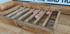 a wooden box filled with lots of eggs on top of a hard wood floor next to a sign