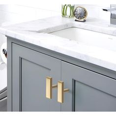 a bathroom sink with marble counter top and gold handles