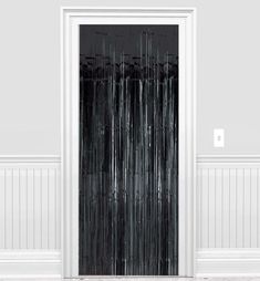 a black and white photo of a door with curtains on the side walk in front of it