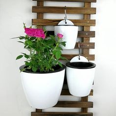 two white planters with pink flowers in them are hanging on a wooden pallet