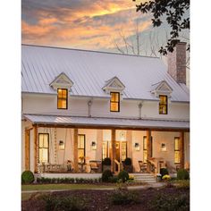 a white house with two story windows and a porch in the front yard at sunset